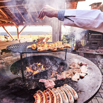 Auf einem großen Grill werden verschiedene Fleischspezialitäten sowie vegetarische Leckereien zubereitet.