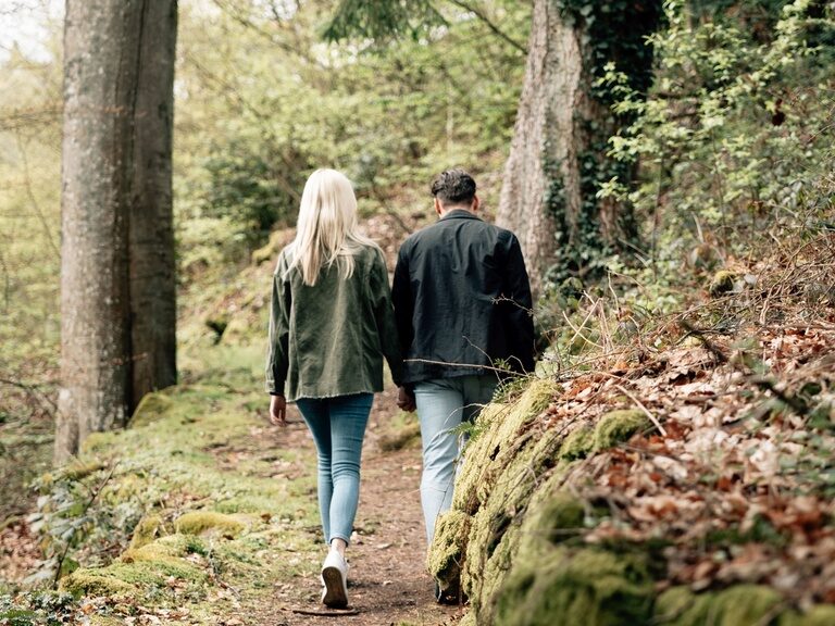 Ein junges Paar das urlaub im Hotel KroneLamm macht spaziert durch einen Wald.