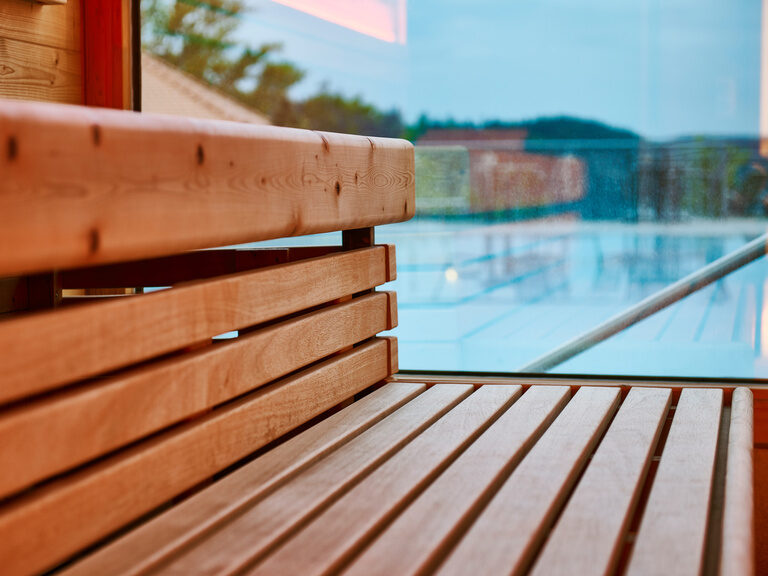 Benches in a sauna separated from the pool by a window.