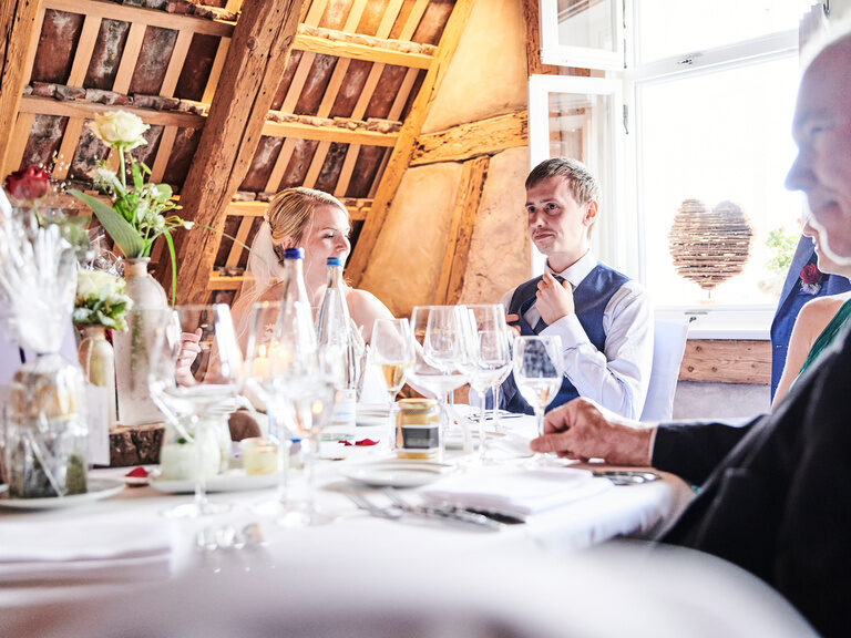 Ein Brautpaar sitz am gedeckten Tisch mit vielen Gläsern im Theurerhof