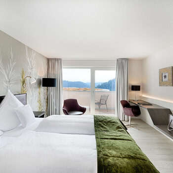 Ein komfortabel eingerichtetes Doppelzimmer mit modischen Möbeln und großen Panoramafenstern.