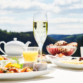 Ein reichlich gedeckter Frühstückstisch auf der Restaurantterrasse mit Blick auf den Schwarzwald im Hintergrund.