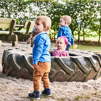 Drei Kinder spielen in einem großen Reifen im Biergarten des Zavelsteiner Wanderheims.