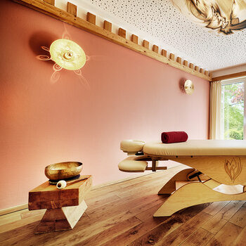 Eine hölzerne Massageliege mit bequemer Auflage steht in einem harmonischen Raum im königSpa des Wellnesshotels KroneLamm