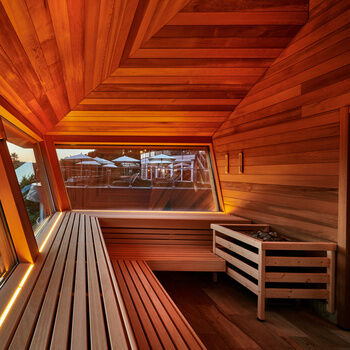 Durch große Fenster einer hölzernen Sauna blickt man in den Schwarzwald.