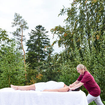 Frau auf einer Massageliege im Außenbereich des königSpa bekommt eine Massage
