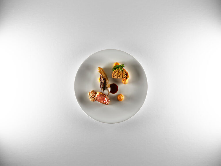 A precisely arranged, white plate with high-quality prepared food.