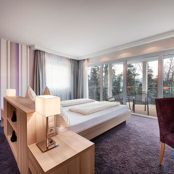 Ein komfortables Doppelbett steht vor einem Panoramafenster mit Blick in den Schwarzwald.