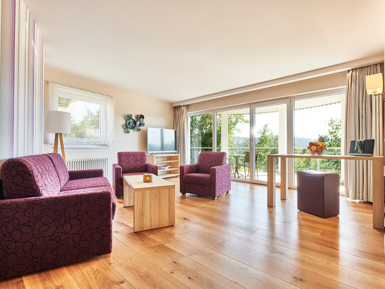 The bright living area of the Kingdom Suite with various fine furniture and wooden floors.