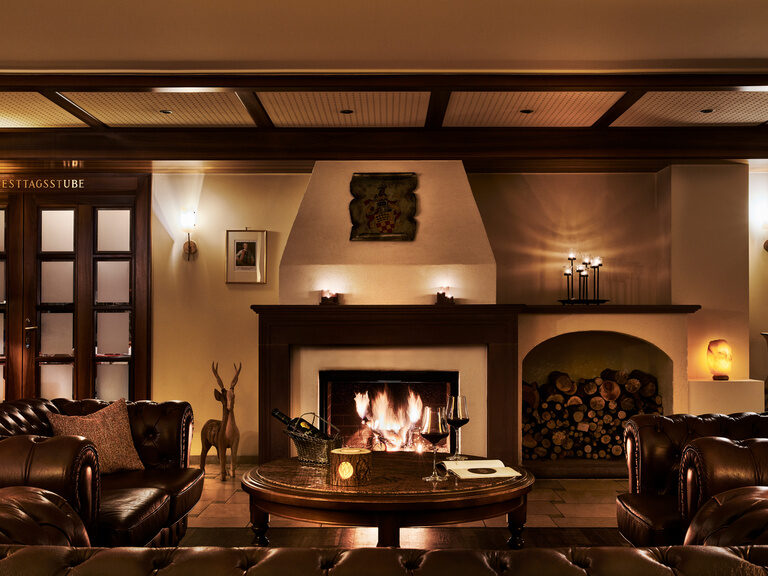 A burning fireplace, comfortable leather couches and two glasses of red wine create a romantic and homely atmosphere.
