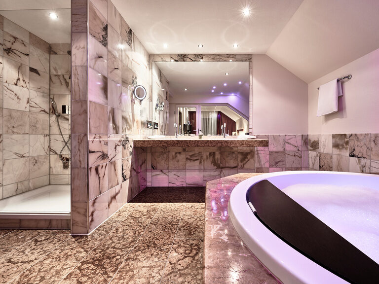 Ein Whirlpool in einem, modernen, mit Marmor ausgestatteten, Badezimmer.
