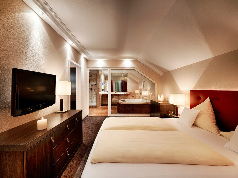 Der geräumige Schlafensbereich mit gemachten Betten in der Jungbrunnensuite im Hotel KroneLamm im Schwarzwald