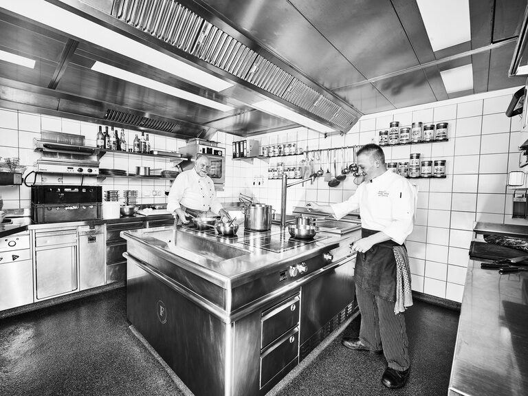 Zwei Köche bei der Zubereitung von Gerichten in der Restaurantküche des Gourmetrestaurants Berlins Krone.