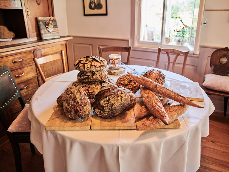 In einer Stube im Theurerhof liegen unterschiedliche Laibe Brot auf einem runden Tisch.