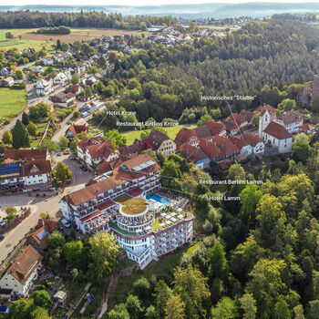 Wellnesshotel Berlins KroneLamm sowie die Stadt Zavelstein umrahmt von grünen Wäldern.