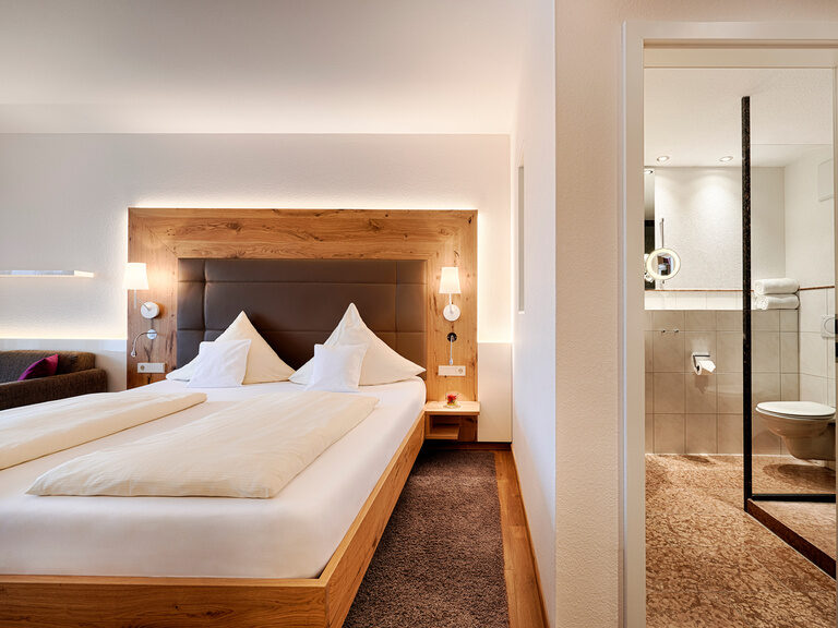 Ein gemütlicher Schlafbereich mit Holzelementen, der durch eine Wand zum Badezimmer getrennt ist.