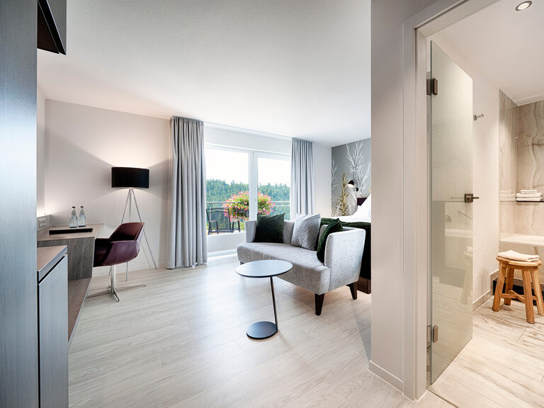 Geräumiges, behaglich eingerichtetes Hotelzimmer, mit angrenzendem Badezimmer in Armaturen in Marmoroptik.