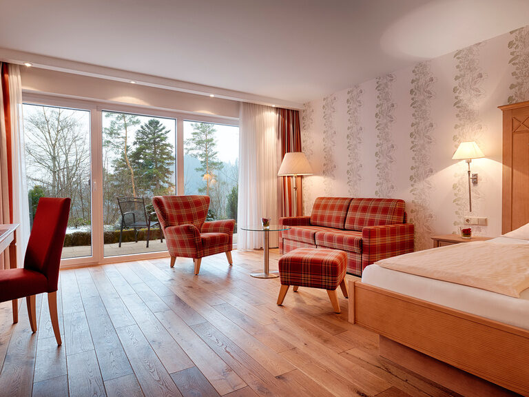 Ein Zimmer mit Holzdesignbodn, gemütlichen Sesseln und anderen Sitzgelegenheiten und großen Panoramafenstern.